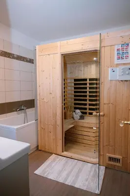 a bathroom with a wooden enclosure with a bath tub at Apartment Kapitan with climbing wall in Kobarid