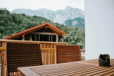 a table and two chairs on a deck with a house at Apartment Kapitan with climbing wall in Kobarid
