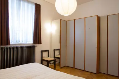 a bedroom with a bed and a chair and a window at Rimska Apartments Tour As Ljubljana in Ljubljana