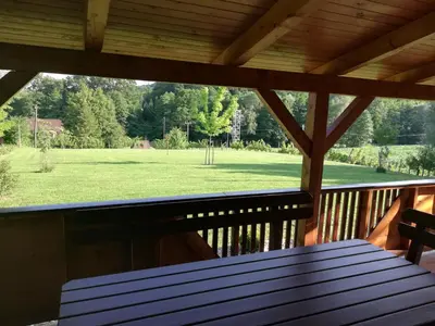 a porch with a wooden table and a view of a field at Brunarica Lorentia in Bizeljsko