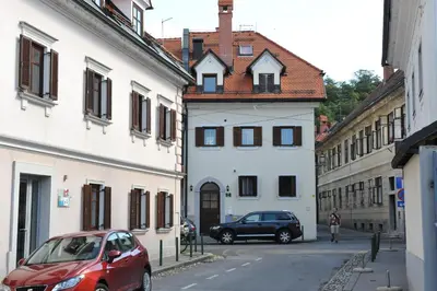 a red car parked next to a white building at Spacious 2-bedroom apartment Zabjak with AC Tour As Ljubljana in Ljubljana