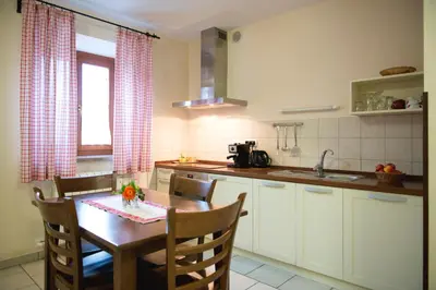 a kitchen with a wooden table and a dining room at Guesthouse Muha in Lipica