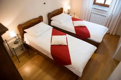 two beds with red and white comforters in a room at Guesthouse Muha in Lipica