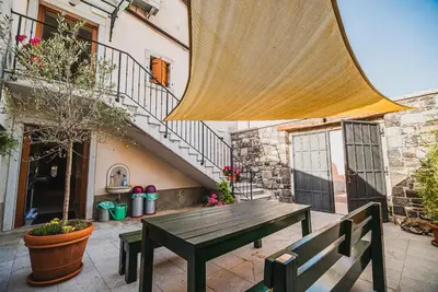 a wooden bench sitting in a courtyard with a staircase at Guesthouse Muha in Lipica