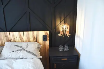 a bedroom with a bed with a black headboard and a lamp at Lesnavesna designer Apartment with a garden in Visoko