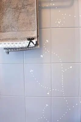 a white tiled bathroom with a bow on the wall at Lesnavesna designer Apartment with a garden in Visoko