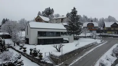 a house with snow on the ground next to a street at Studio ELITE in Bled