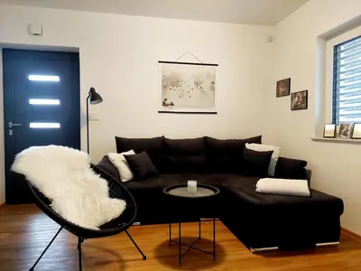 a living room with a black couch and a table at Apartment ALMA - to travel is to live in Celje