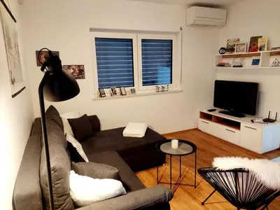 a living room with a couch and a television at Apartment ALMA - to travel is to live in Celje