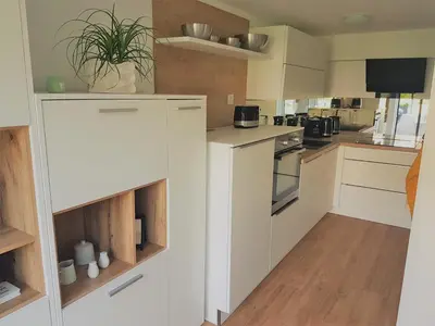a kitchen with white cabinets and wooden floors at Apartment ALMA - to travel is to live in Celje