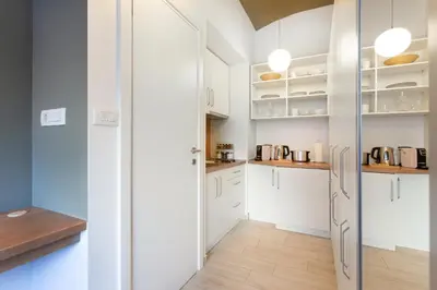 a kitchen with white cabinets and a wooden floor at Apartments Tivoli in Ljubljana