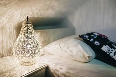 a lamp sitting on a bed next to a pillow at Grom Ribno Apartments in Bled