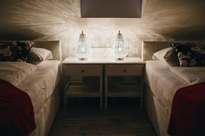 two beds in a room with two lamps on them at Grom Ribno Apartments in Bled