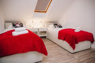 two beds in a room with a red blanket on them at Grom Ribno Apartments in Bled