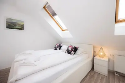 a white bedroom with a white bed with two pillows at Grom Ribno Apartments in Bled