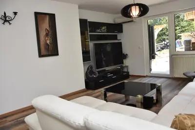 a living room with a white couch and a tv at Planika Holiday Home in Bled