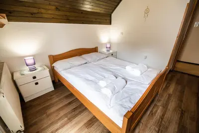 a bedroom with a bed with two night stands and two lamps at Home away from home in Bohinj