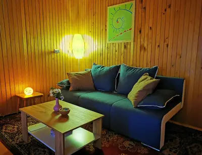 a living room with a blue couch and a table at MERIKOTKA - a cozy wooden cottage, sLOVEnia in Braslovče