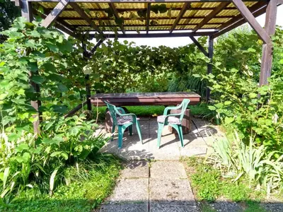 a picnic table and two chairs in a garden at MERIKOTKA - a cozy wooden cottage, sLOVEnia in Braslovče