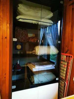 a glass display case in a room with beds at MERIKOTKA - a cozy wooden cottage, sLOVEnia in Braslovče