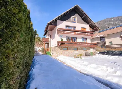 a house with snow in front of it at Apartments and Rooms Banić in Kranjska Gora