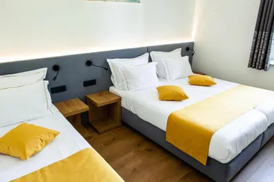 two beds with yellow pillows in a room at Hotel Vila Pohorje in Slovenj Gradec