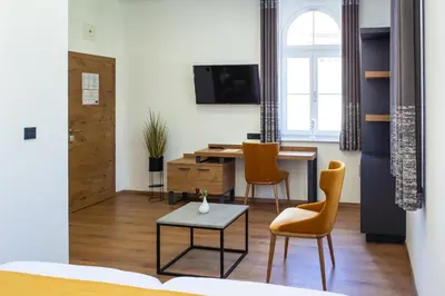 a living room with a table and chairs at Hotel Vila Pohorje in Slovenj Gradec