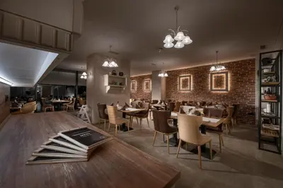 a restaurant with tables and chairs and a brick wall at Hotel Vila Pohorje in Slovenj Gradec