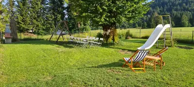 a couple of chairs and a slide in the grass at Počitniška hiša Ostrnica in Hrib-Loški Potok
