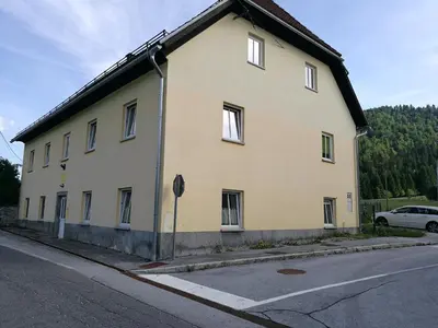 a large white building on the side of a street at Počitniška hiša Ostrnica in Hrib-Loški Potok