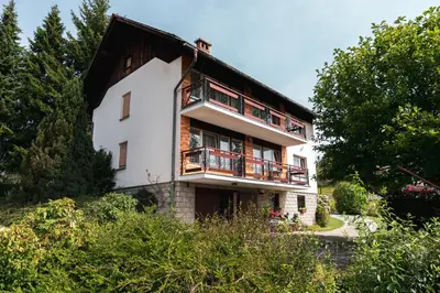 a white house with a balcony and trees at Apartmaji Retro in Spodnje Gorje
