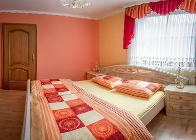a bedroom with orange walls and a bed with pillows at APARTMA AJDA in Komenda