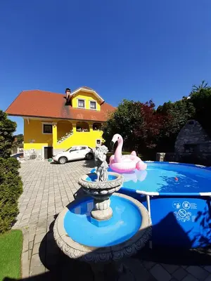 a fountain in front of a house with a swimming pool at APARTMA AJDA in Komenda