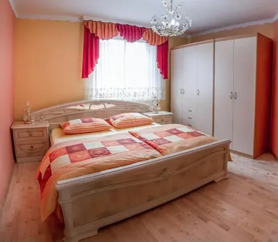 a bedroom with a large bed and a chandelier at APARTMA AJDA in Komenda