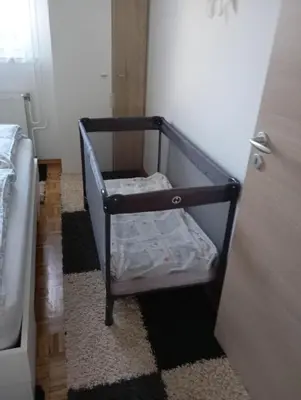 a small crib in a room with a door at Apartma JERMAN - Cerknica in Cerknica