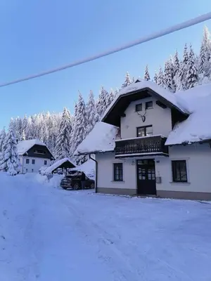 a snow covered building with a car parked in front at Apartman Irvin in Kranjska Gora
