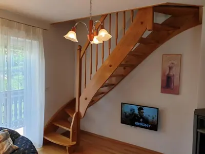 a wooden staircase in a living room with a tv at Apartman Irvin in Kranjska Gora