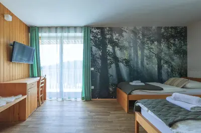 a bedroom with two beds and a mural of trees at Hotel Jelka Pokljuka in Goreljek