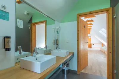 a bathroom with two sinks and a mirror at Hotel Jelka Pokljuka in Goreljek