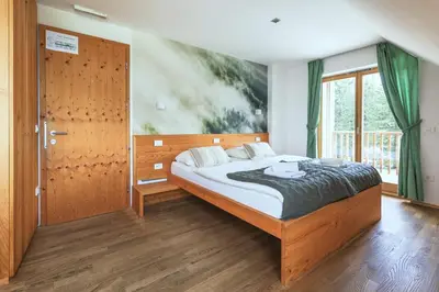 a bedroom with a bed and a large window at Hotel Jelka Pokljuka in Goreljek