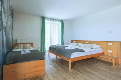 a bedroom with two beds and a large window at Hotel Jelka Pokljuka in Goreljek