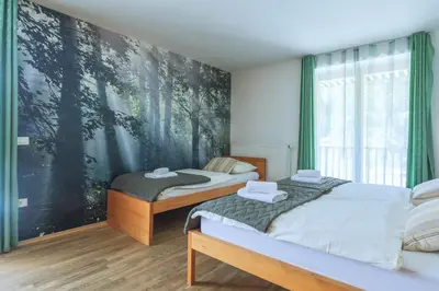 two beds in a bedroom with a painting on the wall at Hotel Jelka Pokljuka in Goreljek