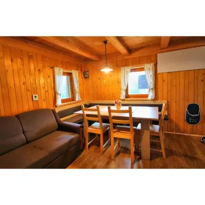 a living room with a couch and a table and chairs at Počitniška hiša Jeklar in Bohinj