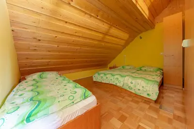two beds in a room with a wooden ceiling at Koča na Krvavcu in Cerklje na Gorenjskem