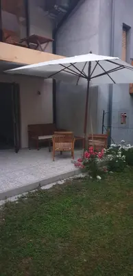 a patio with two benches and an umbrella at APARTMAJI VITEZ apartma 1 in Bovec