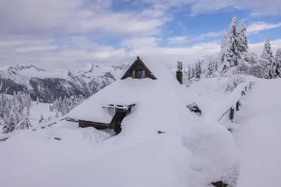 a snow covered house on top of a mountain at Koča Zlatorog - Velika planina in Stahovica