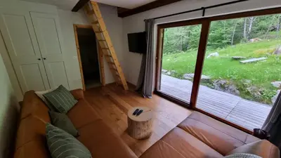 a living room with a couch and a large window at Cozy Private Cabin in the heart of Triglav National Park in Trenta