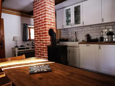 a kitchen with a wooden table and a brick wall at Cozy Private Cabin in the heart of Triglav National Park in Trenta