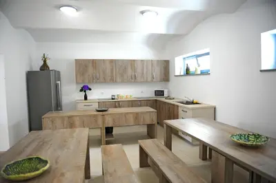 a kitchen with wooden tables and a stainless steel refrigerator at Hostel Ormož in Ormoz