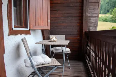 a table and two chairs on a porch at Wooden Cottage in Jesenice